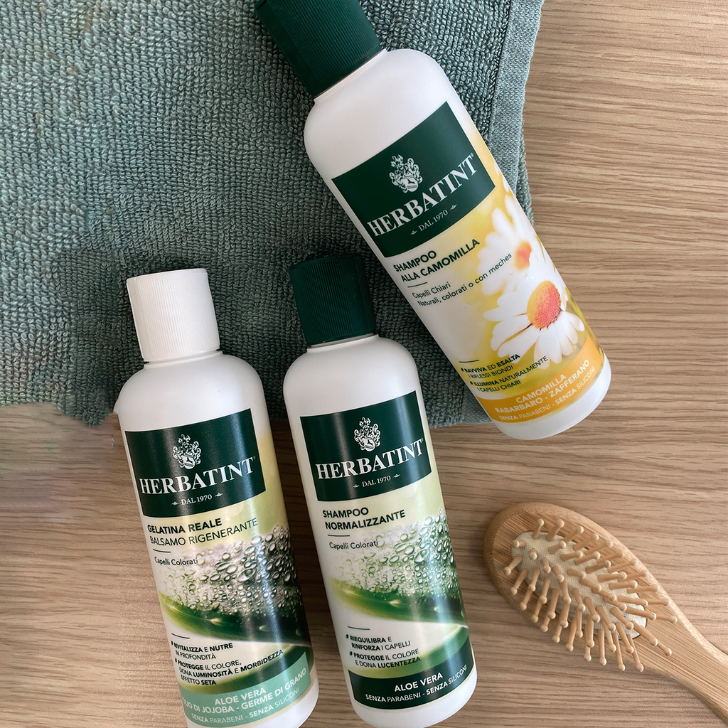 Herbatint Aloe Vera shampoo and conditioner lying a towel with a brush beside the bottles.